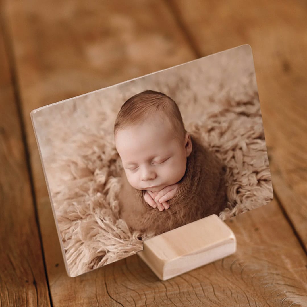 Foto de bebê dormindo em fundo de pelúcia, impressa em quadro de madeira, decorativo e personalizado.